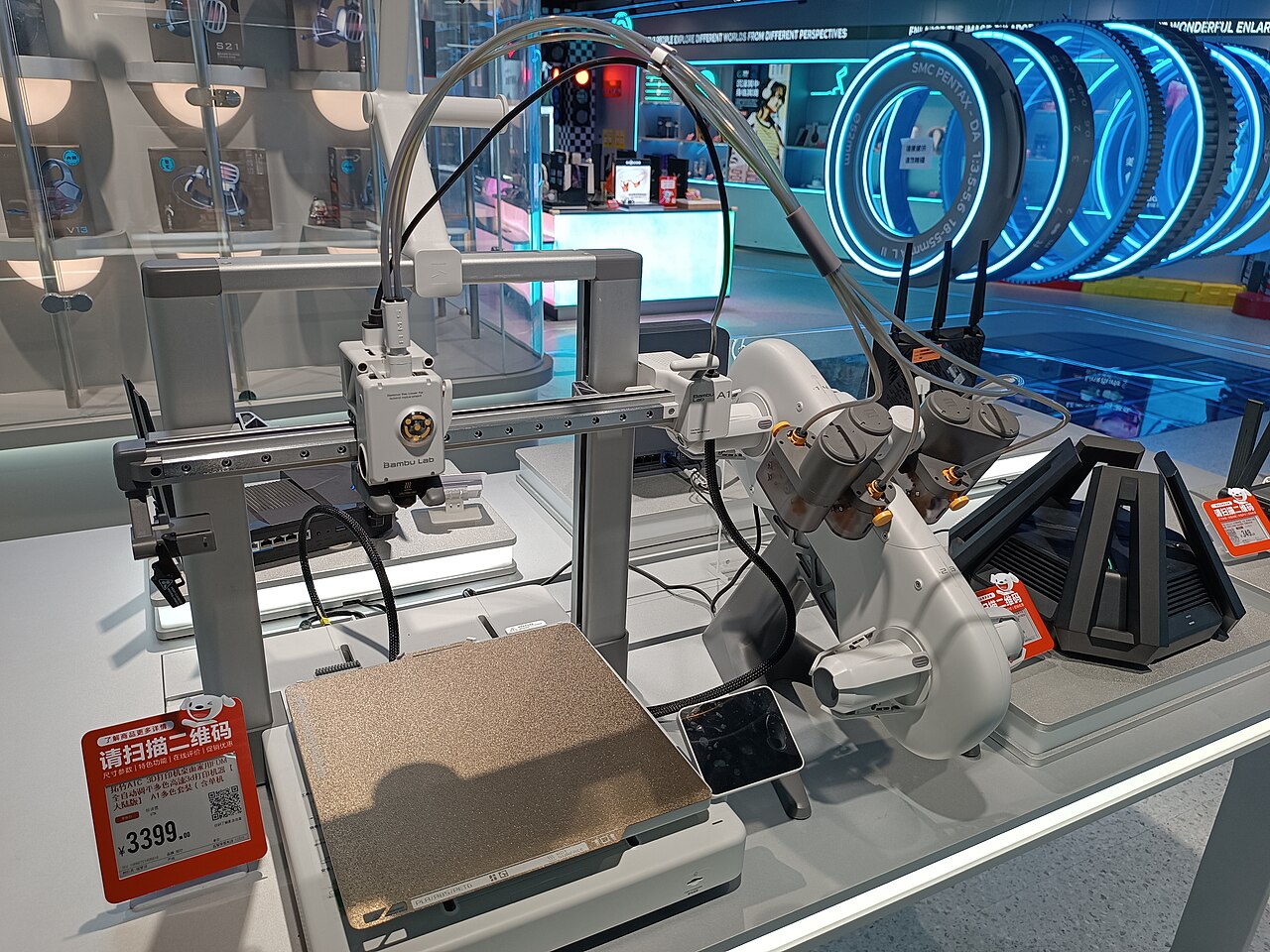 Bambu Lab A1 beside an AMS lite feeder on an electronics showroom display.
